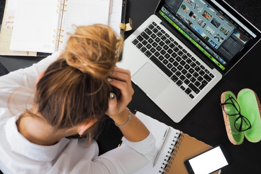 Woman at her desk, hanging her head in frustration