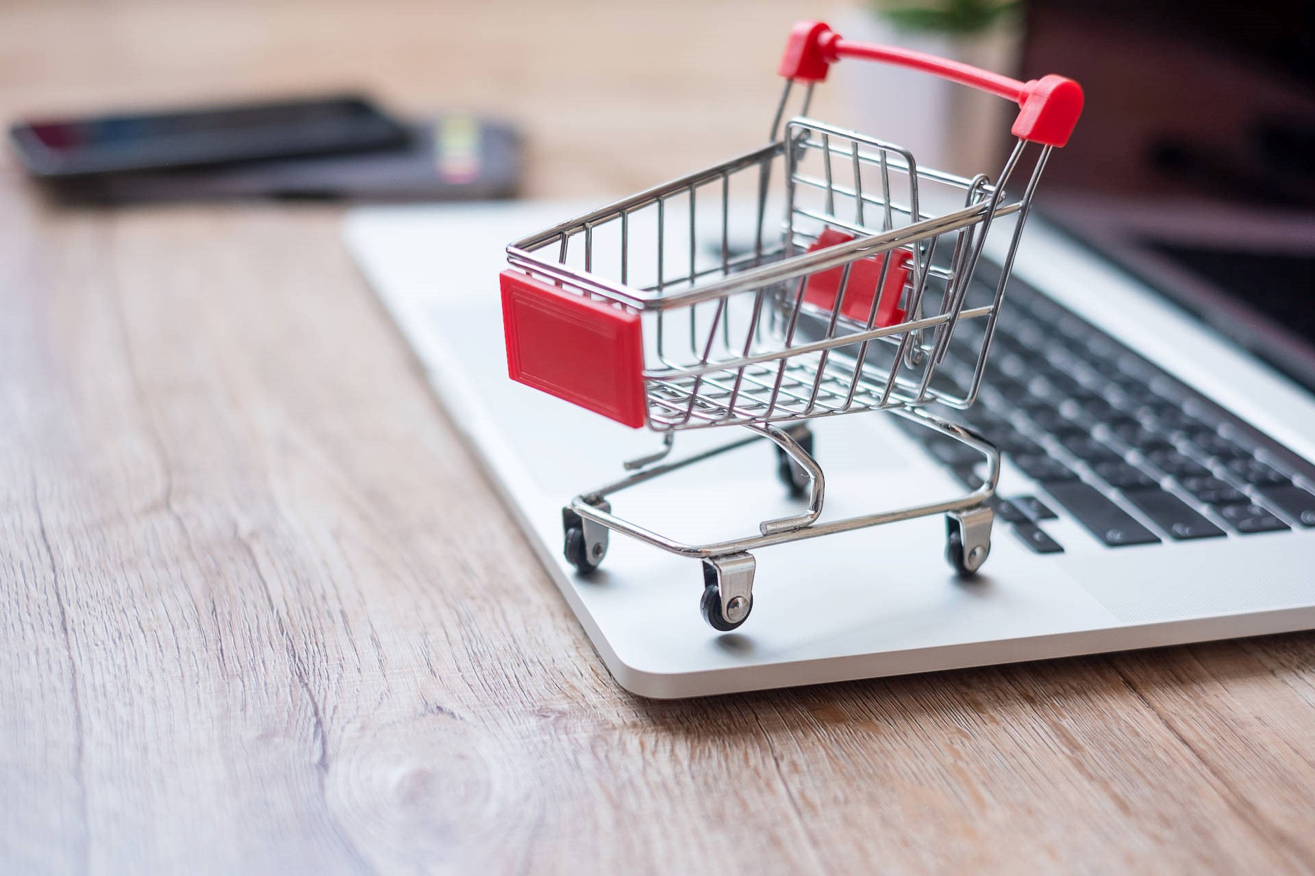 Miniature shopping cart sitting on a laptop computer