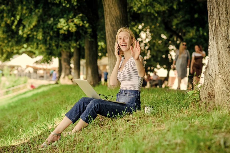Young woman with laptop and mug working productively outdoors
